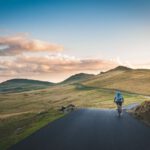 Road Trip Packing - person cycling on road distance with mountain during daytime