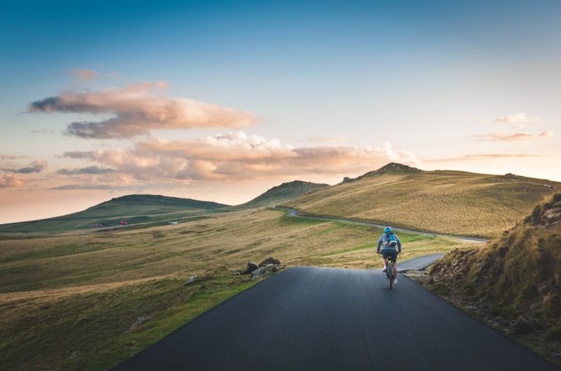 Road Trip Packing - person cycling on road distance with mountain during daytime