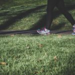 Walking Shoes - shallow focus photography of person walking on road between grass