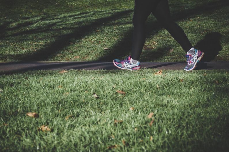 Walking Shoes - shallow focus photography of person walking on road between grass