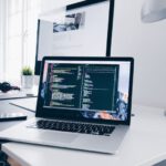 Portable WiFi - A MacBook with lines of code on its screen on a busy desk