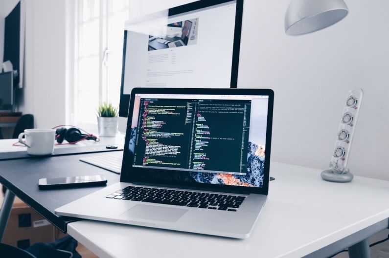 Portable WiFi - A MacBook with lines of code on its screen on a busy desk