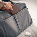 Packing Cubes Review - a person holding a wallet in a bag on a bed