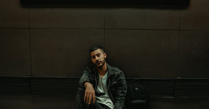 Loneliness Travel - A Man Sitting on the Floor by the Wall with a Sign