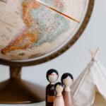 Family Destinations - From above of miniature toys tipi house and American Indian family placed near vintage globe against gray background at daytime