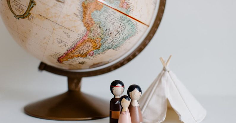 Family Destinations - From above of miniature toys tipi house and American Indian family placed near vintage globe against gray background at daytime
