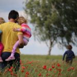 Family Activities - man carrying to girls on field of red petaled flower