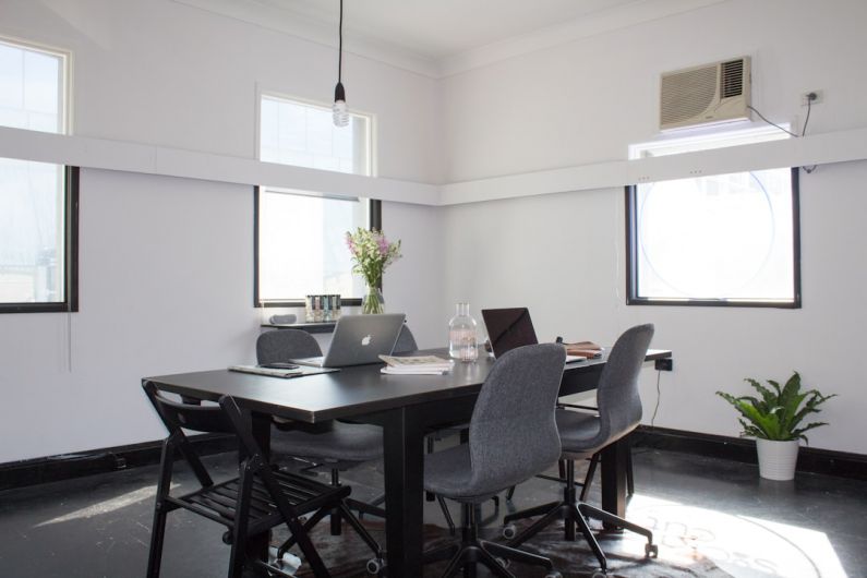 Networking Nomad - rectangular brown wooden table with six chairs and silver MacBook on top