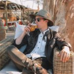 Nomad Country - man in black leather jacket and brown pants sitting on blue wooden bench during daytime