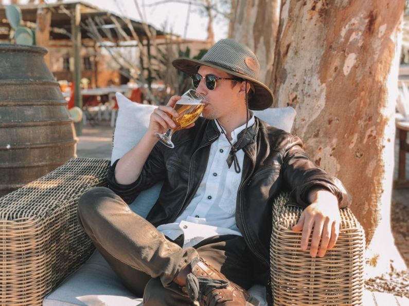 Nomad Country - man in black leather jacket and brown pants sitting on blue wooden bench during daytime