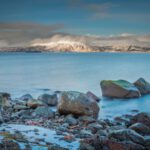 Fjord View - gray and brown rocks near body of water under cloudy sky during daytime