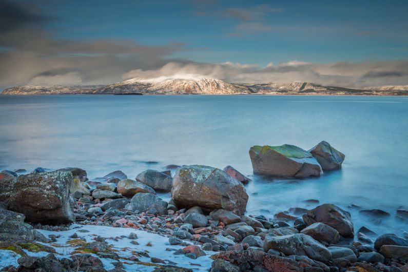 Fjord View - gray and brown rocks near body of water under cloudy sky during daytime