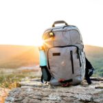 Backpack - grey and black hiking backpack and cyan tumbler on grey rock during sunset