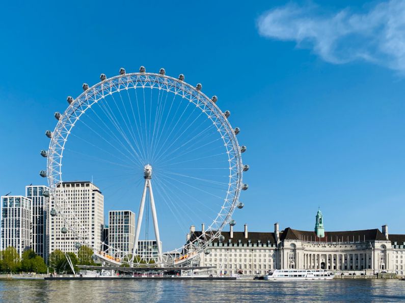 London Eye - white ferris wheel near white concrete building under blue sky during daytime