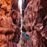 Rock Climbing - a man climbing up the side of a canyon