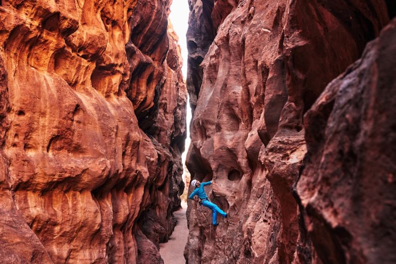 Rock Climbing - a man climbing up the side of a canyon
