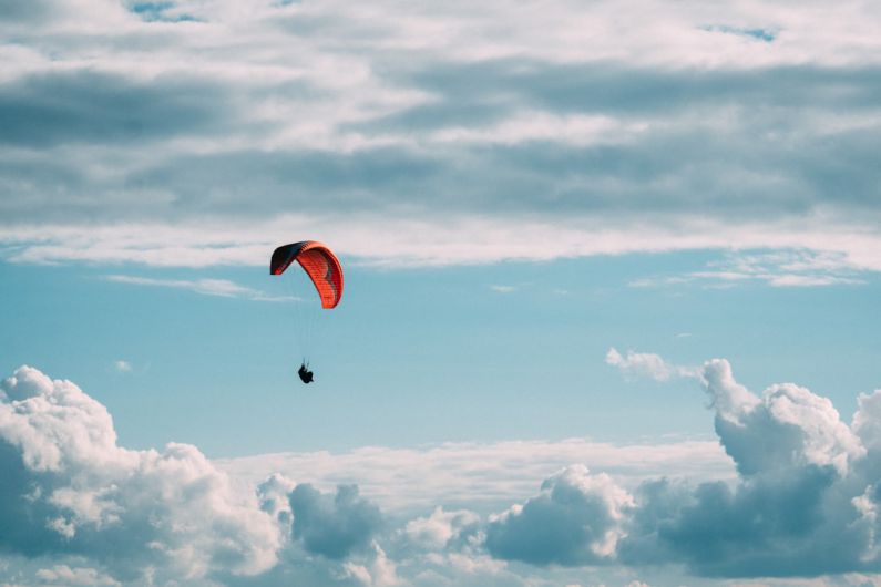 Parachute - person in red parachute under white clouds during daytime