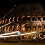 Colosseum Night - a large stone building with arches with Colosseum in the background