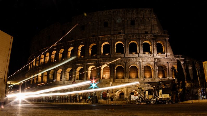 Colosseum Night - a large stone building with arches with Colosseum in the background