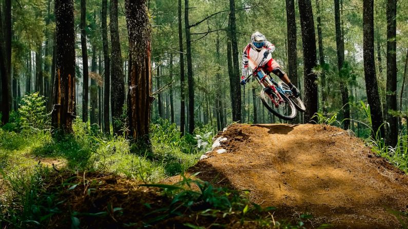 Mountain Bike - man riding bike doing stunt near green trees during daytime