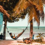 Beach Hammock - man on hammock while using smartphone beside seashore
