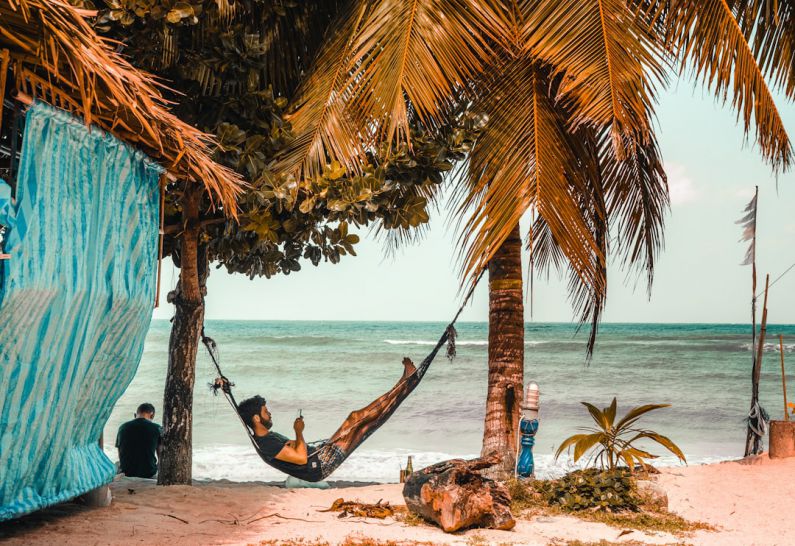 Beach Hammock - man on hammock while using smartphone beside seashore